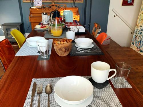 a wooden table with white bowls and cups on it at Dylan Thomas Sea View in Laugharne