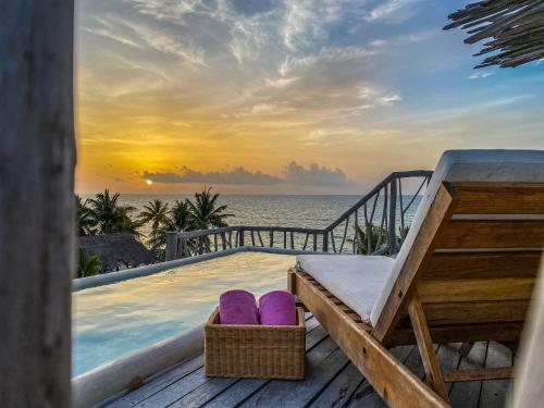 a resort plunge pool with purple cushions and a sunset at Punta Blanca Beach House in Costa Mujeres