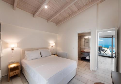 a white bedroom with a bed and a view of the ocean at Avraam Sunset Villas with Private Heated Pools by Imagine Lefkada in Kalamitsi