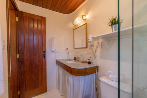 a bathroom with a sink and a toilet and a mirror at Pousada Recanto do Arraial in Arraial d'Ajuda
