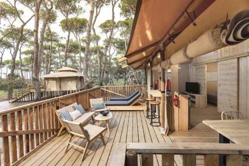 una terrazza in legno con sedie e una televisione di ISOLA VERDE Camping Village a Nettuno