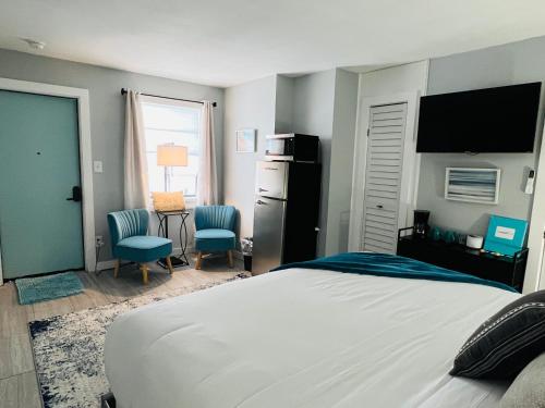 a bedroom with a bed and two chairs and a television at 1915 Beach Club in Daytona Beach