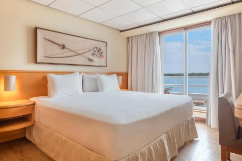 a bedroom with a large bed and a large window at Grand Amazon Expedition in Manaus