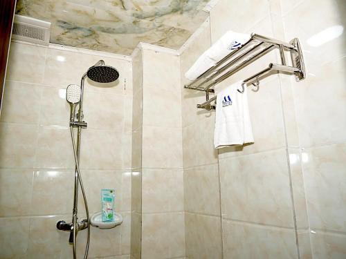 een badkamer met een douche, een wastafel en handdoeken bij Marriot Metropolitan Hotel in Douala