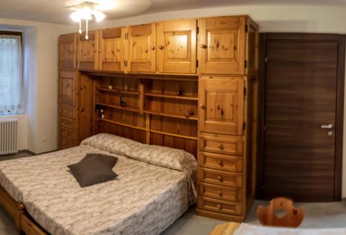 Residenza Cotruta Spiazzo في سبياتزو: غرفة نوم مع سرير وخزانة خشبية كبيرة