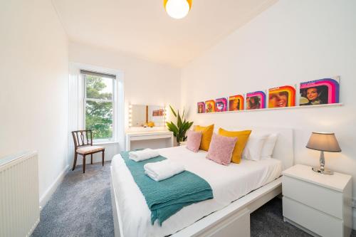 een witte slaapkamer met een groot bed met kleurrijke kussens bij The Palais in Dundee