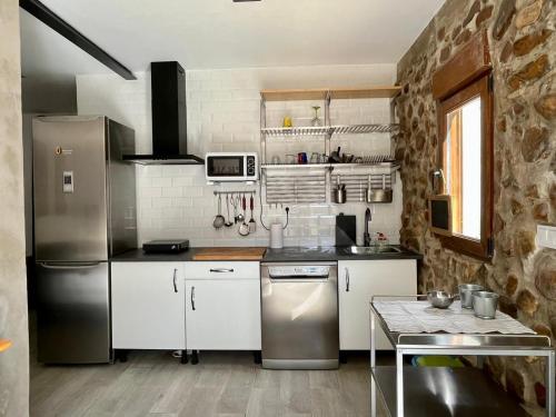 a kitchen with white cabinets and a stainless steel refrigerator at Stone Garden, Casa en plena naturaleza in Uceda