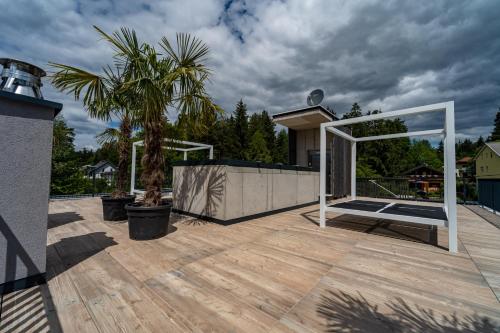 a deck with a palm tree on a house at Merlrose Apartments in Sankt Kanzian