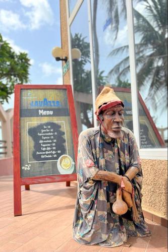 an old man sitting in front of a sign at Tropic Garden Hotel in Bathurst