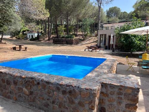 a swimming pool in a stone wall next to a yard at Stone Garden, Casa en plena naturaleza in Uceda