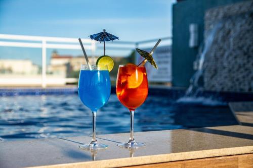 two cocktails sitting on a table next to a swimming pool at Casa Nova Hotel in Rio de Janeiro