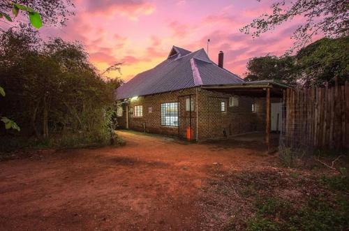 a brick building with a sunset in the background at Kruger Wild Dog Inn in Marloth Park