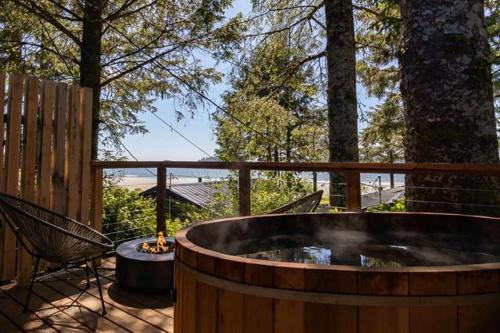 une grande baignoire en bois assise sur une terrasse avec une chaise dans l'établissement Mackenzie Beach Resort, à Tofino