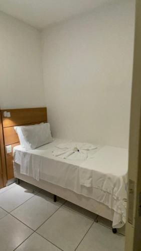 a small bedroom with a bed with white sheets at Pousada Ilha Vitoria in Ubatuba