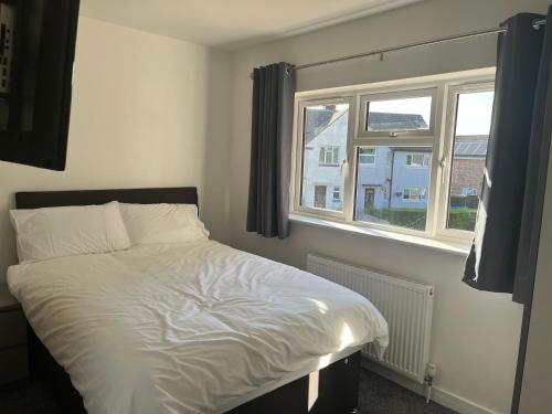 a bedroom with a white bed and a window at House - Sleeps 14 onsite parking & pets allowed in Poole