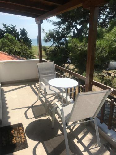 two chairs and a table on a porch with the ocean at Irini’s Attic in Nea Irakleia