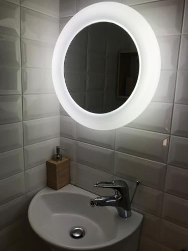 a bathroom with a sink and a white mirror at Irini’s Attic in Nea Irakleia