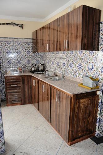 a kitchen with wooden cabinets and a sink at Dar Benyounes in Benguerir