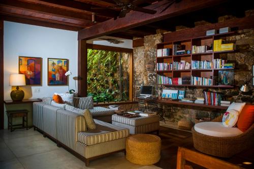 a living room with a couch and a book shelf at Casa Turquesa - Maison D´Hôtes in Paraty