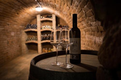 a bottle of wine and two wine glasses on a barrel at Sklep Mozajka in Velké Bílovice