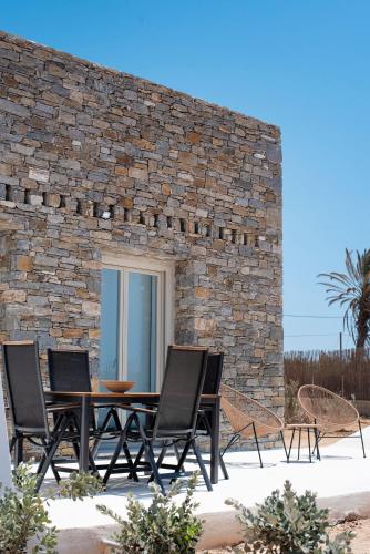 a patio with a table and chairs and a stone wall at CAMPO SUITES in Kampos Paros