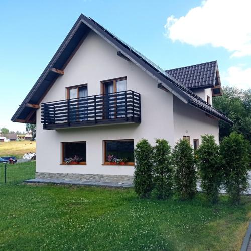 Cette maison blanche dispose d'un balcon et de quelques buissons. dans l'établissement domek u fiedora, à Pieniążkowice