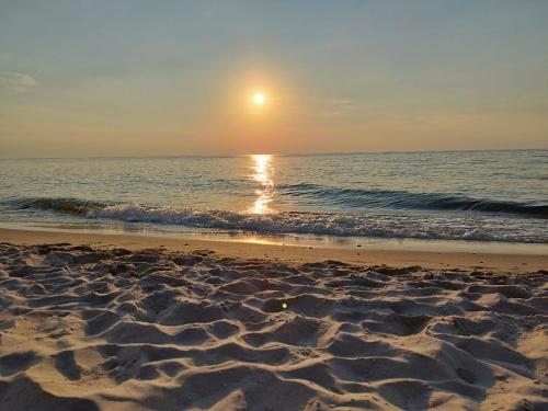 a beach with the sun rising over the ocean at Kamienica Mielno in Mielno