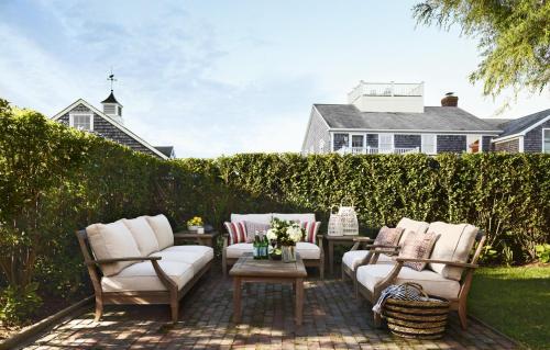 a patio with white couches and tables and a fence at 52 Union in Nantucket