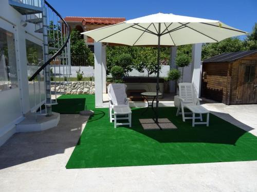 patio ze stołem, krzesłami i parasolem w obiekcie Apartment Elite w Rogoznicy