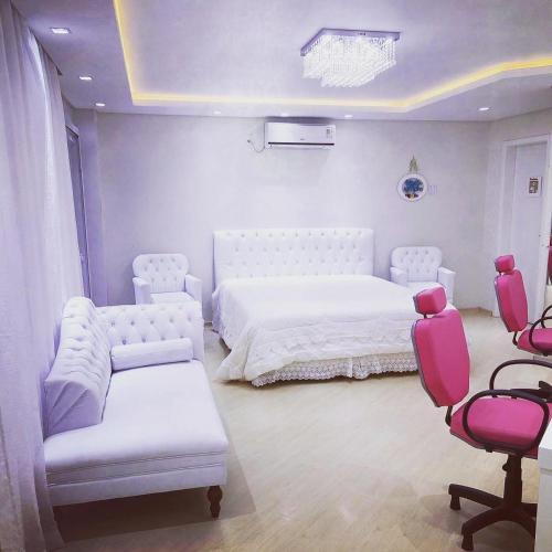 a bedroom with a white bed and pink chairs at Paraíso do Salto in Lages