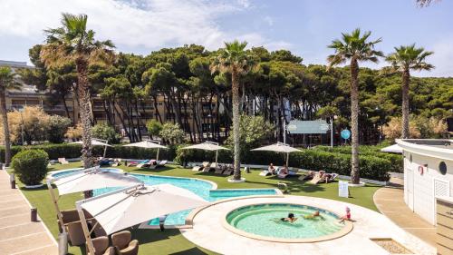 une image d'une piscine dans un complexe avec des palmiers dans l'établissement Hotel Astor, à Alba Adriatica