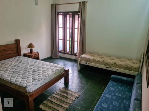 two beds in a room with two windows and a room with at Hospedaria do Ernesto in Itanhandu