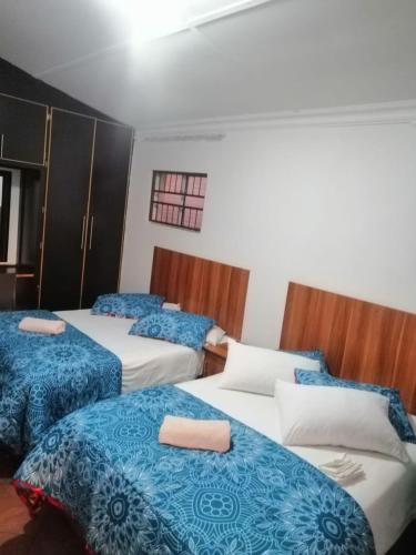 Habitación con 3 camas con sábanas azules y blancas. en House Ebenezer en Bloemfontein