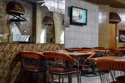 un restaurante con mesas y sillas y TV en Hotel Acuarius en La Plata