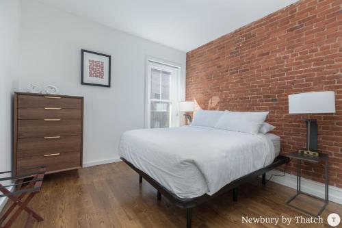Un dormitorio con una pared de ladrillo y una cama en 304 Newbury Street by Thatch, en Boston