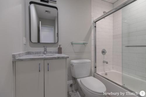 a bathroom with a toilet and a sink and a mirror at 304 Newbury Street by Thatch in Boston