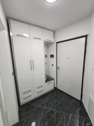ein Badezimmer mit weißen Schränken und schwarzem Fliesenboden in der Unterkunft Apartman Park Lake in Tuzla