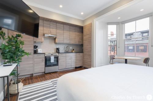 a kitchen with wooden cabinets and a white bed in a room at J Miller Flats by Thatch in Boston