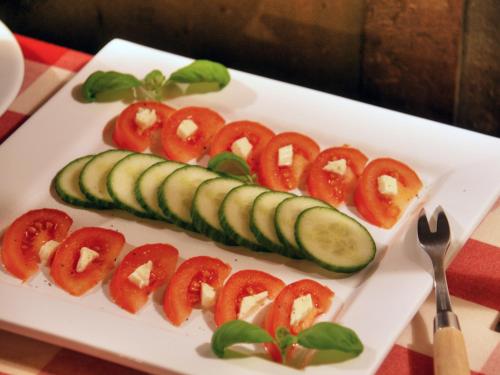 a plate of food with cucumbers and tomatoes at Hotel Grüner Baum in Würzburg