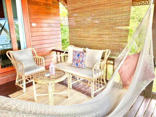 a porch with a hammock and two chairs and a table at Hin Kong Sunset Beach Front House in Srithanu
