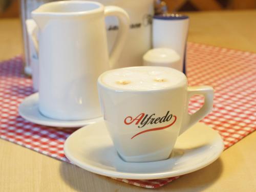 a cup of coffee on a plate on a table at Hotel Grüner Baum in Würzburg