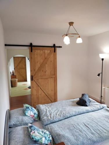 a bedroom with a barn door and a bed with pillows at Apartament Sielsko-Wiejsko in Szczytna