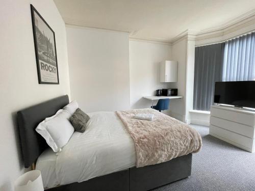a bedroom with a bed and a flat screen tv at St Peter's Shared House in Birmingham