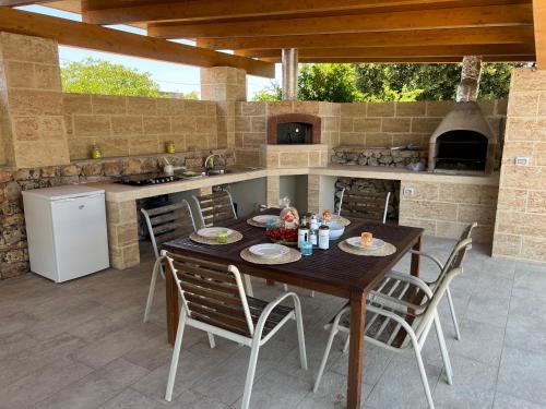 an outdoor kitchen with a wooden table and chairs at L’Incanto in Corsano