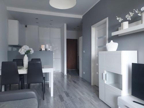 Modern Apartment - Francuska Park في كاتوفيسي: غرفة طعام مع طاولة بيضاء وكراسي سوداء
