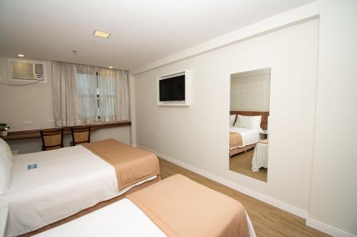 a hotel room with two beds and a mirror at Casa Nova Hotel in Rio de Janeiro