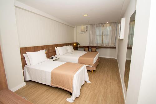 a hotel room with two beds and a window at Casa Nova Hotel in Rio de Janeiro