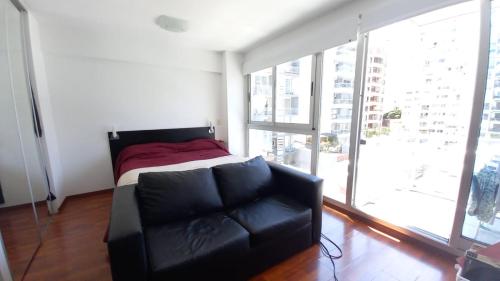 un sofá de cuero negro en una habitación con una gran ventana en Aparts Zapata, Palermo Hollywood en Buenos Aires