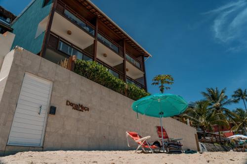 a beach chair and an umbrella on the sand in front of a building at Pousada Dona Moça in Morro de São Paulo