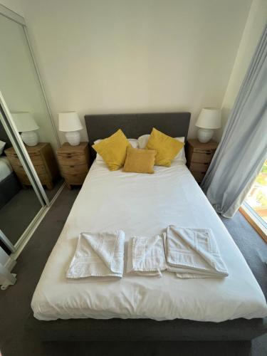 a bedroom with a bed with white sheets and yellow pillows at City Centre Luxury Apartments in Belfast